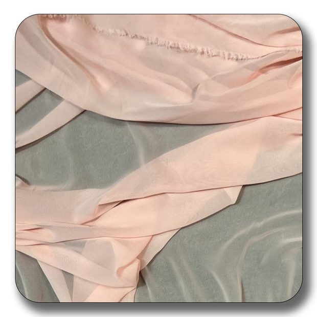 Soft pink polyester chiffon fabric displayed on a smooth surface, ideal for sewing and crafting projects.
